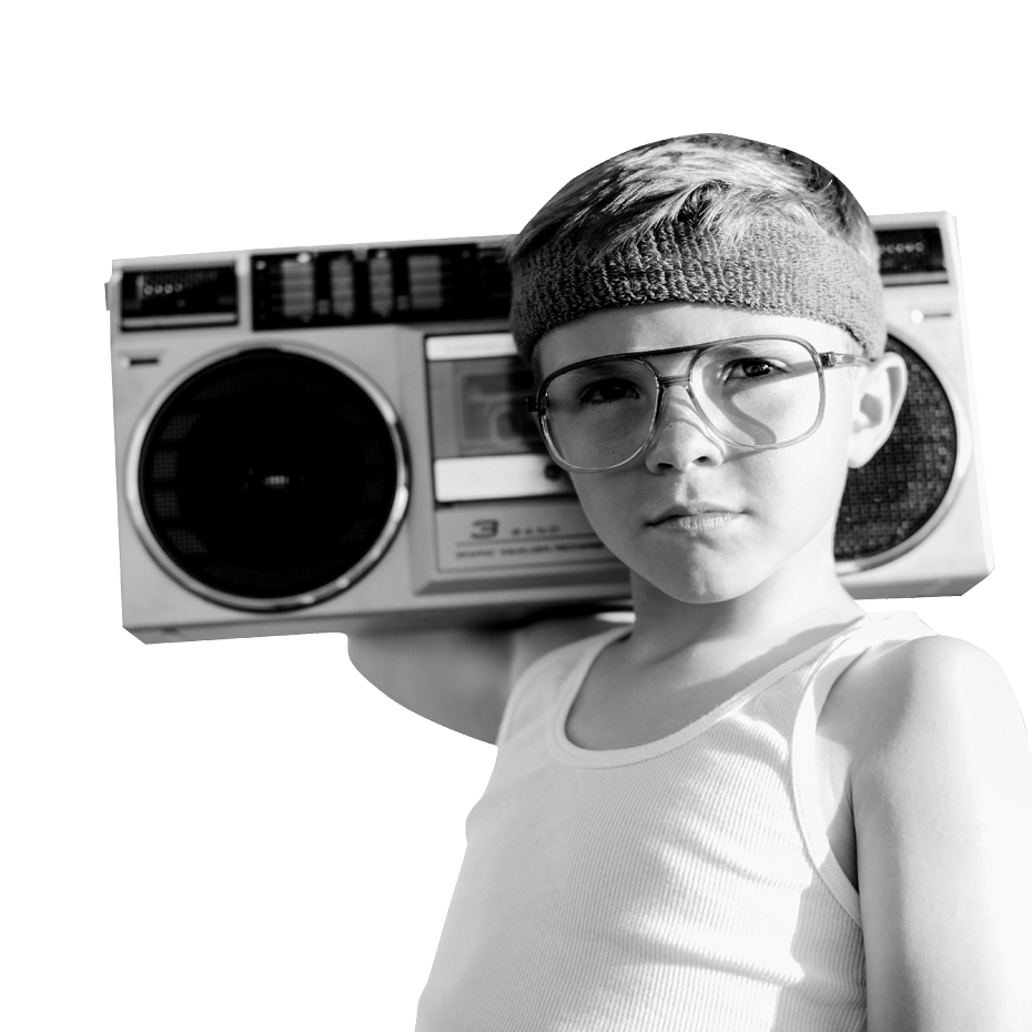 Ein kleiner Junge mit Brille und Stirnband hält einen Kassettenrekorder auf der rechten Schulter und schaut in die Kamera.